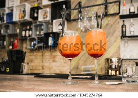 Glass of orange cocktail with a straw on the background of a bar counter.