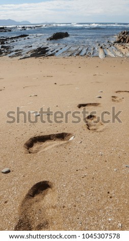 footprint on sand, ocean and rocks on background