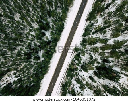 Aerial Drone Photography of a Road in Winter, Between Woods with a Snow on a Cloudy Day