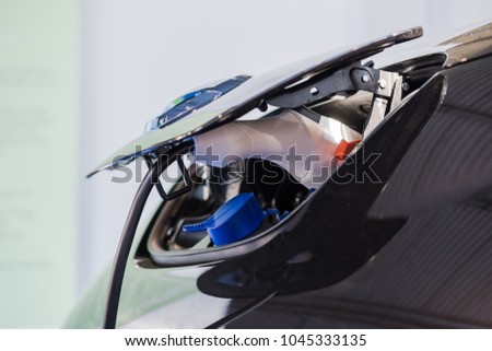 Close up of the Hybrid car electric charger station with power supply plugged into an electric car being charged. Royalty-Free Stock Photo #1045333135