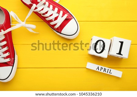 Calendar cubes with red sport shoes on yellow wooden table