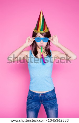young woman with party hat and noisemaker on the pink background