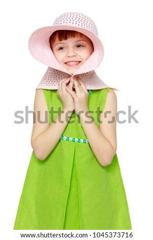 A little girl with long blond hair and a short bangs, in a short summer dress.A girl is posing in a beach straw hat.