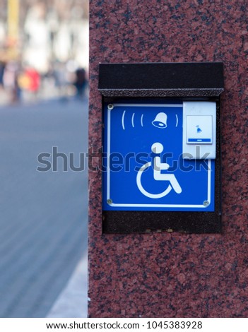 Handicapped access entrance pad mounted to a wall. Sign a button for a visa for people with disabilities