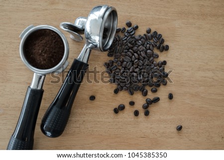 An two espresso handle filled with ground coffee and seed Placed on a wooden floor