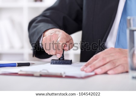 ManÃ¢Â?Â?s hand stamping documents, close-up Royalty-Free Stock Photo #104542022