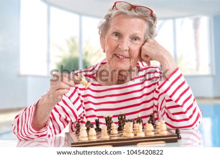 Senior old woman playing chess, moving pieces across the chessboard