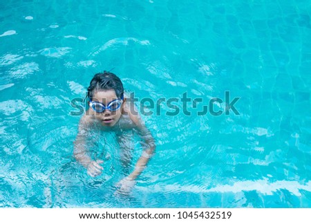 Asian young boy splashing in swimming pool 