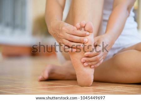 Closeup young woman feeling pain in her foot at home. Healthcare and medical concept. Royalty-Free Stock Photo #1045449697