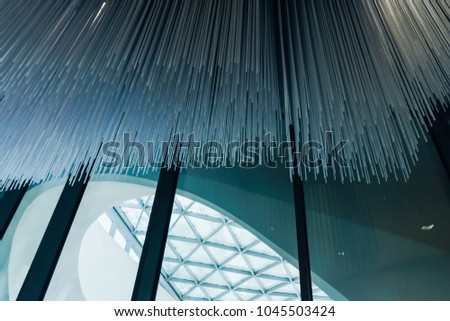 Modern futuristic ceiling in the form of a wave of long tubes with different heights and bright lights from below
