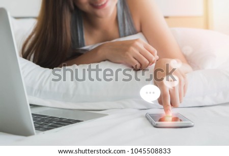 Asian Women using smartphone with laptop on white bed in bedroom and Chat icon.Concept of people use technology.