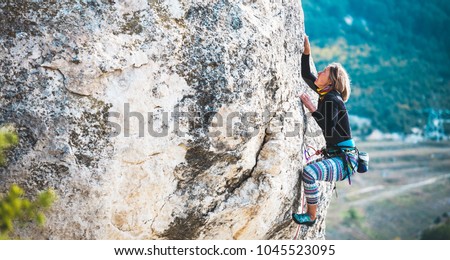 The girl climbs the rock. The climber trains on a natural relief. Extreme sport. Active recreation in nature. A woman overcomes a difficult climbing route. Royalty-Free Stock Photo #1045523095