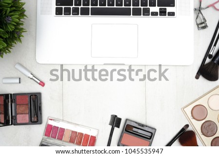 Feminine workspace border with notebook keyboard, coffee and make up brushes, top view and copy space