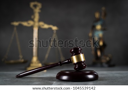 Law and Justice concept. Mallet of the judge, books, scales of justice. Gray stone background, reflections on the floor, place for typography. Courtroom theme.