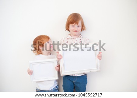 Two redhead children with frames in their hands