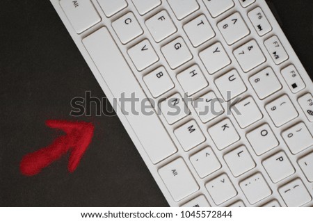 red arrow points to a white keyboard. Black background, top view.