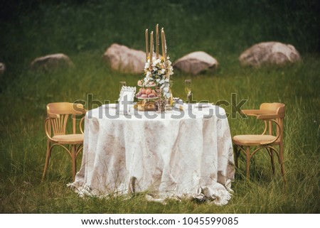 Romantic table with flowers and candles in the middle of the meadow.