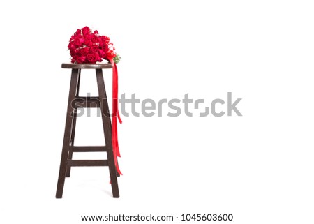 Red roses bouquet placed on a wooden chair on a white background.
