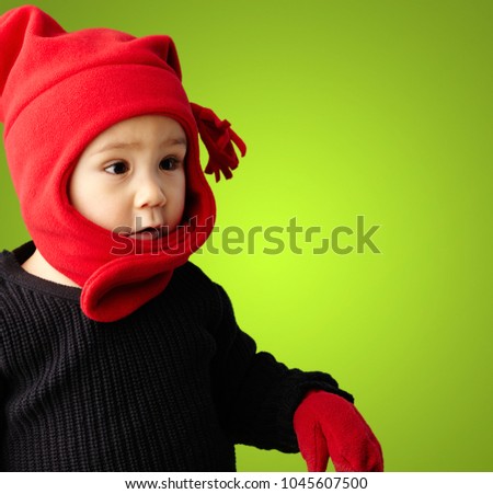 Portrait Of Child Wearing Warm Clothing against a green background