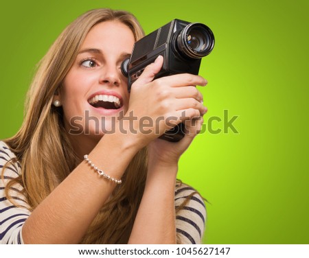 Woman Looking Through A Camera against a green background