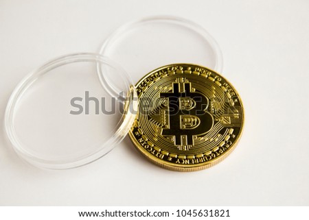 A real, golden, physical symbol of Bitcoin with plastic case on white background