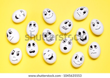 Eggs with drawn cartoon faces with various emotions on yellow background