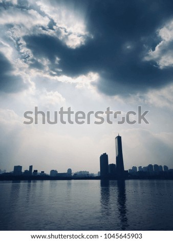 Buildings stand on the riverside under silver lining cloud in the afternoon.
