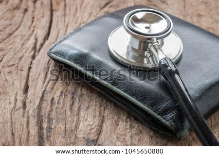 A photo of stethoscope and old black wallet. This photo shoot in concept Financial health chech up