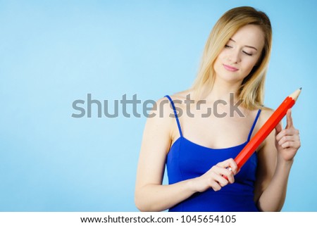 Woman confused thinking seeks a solution. Pensive thoughtful schoolgirl or female student coming up with an idea, holding big red pencil. Studio shot on blue.