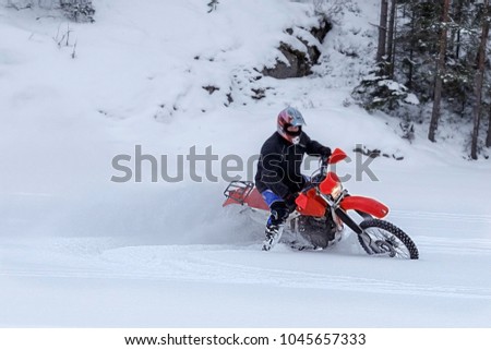 Motorcyclist on a crossover motorcycle rides in the snow. Turn of wheels a spray of snow 