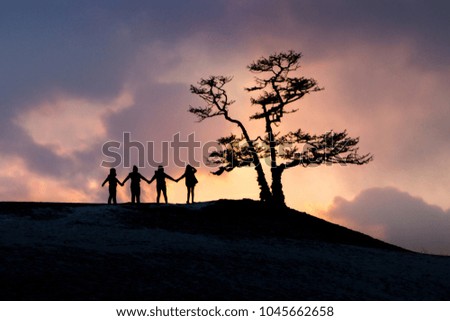 Silhouette of happy business team hold their hand together in sunset sky background and tree beside for business teamwork concept