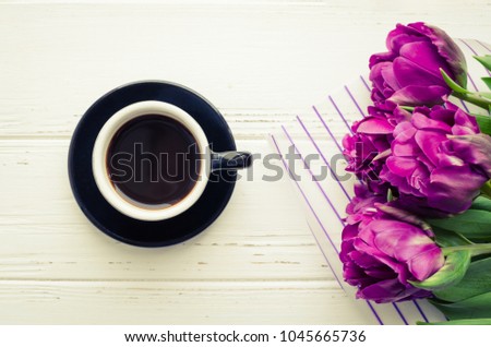 Coffee and flowers tulip. Cup of coffee and purple tulips on white wooden table. Breakfast on Mothers day, Valentines Day or Womens day. Spring background. Copy space. Top view. Flat lay.