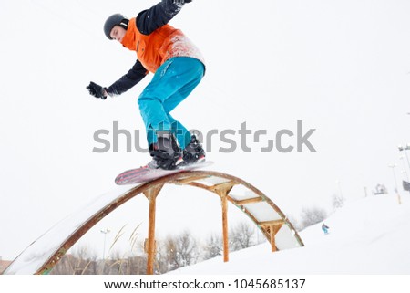 Photo of sportive man skiing on snowboard with springboard