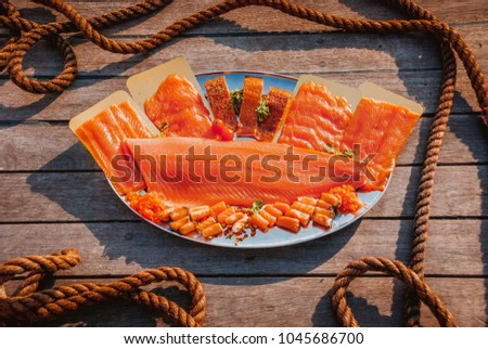 Smoked salmon products placed on a tray. Picture taken on the wooden deck of the ship.