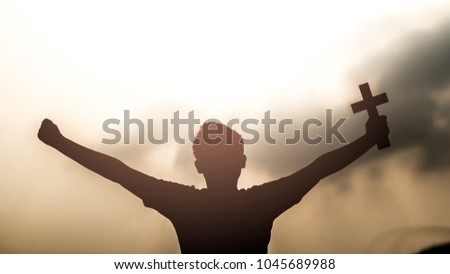 Human hand holding and christian cross with light sunset background