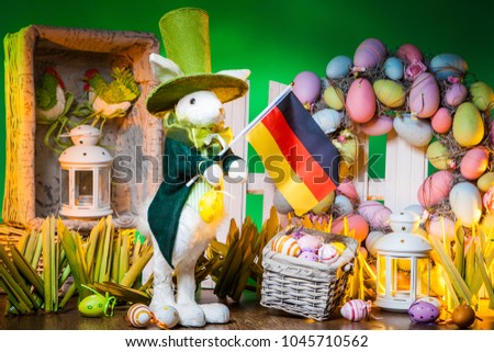 The Feast of Easter. Rabbit with colorful eggs. Easter holiday in Germany. A flag of Germany is holding an Easter bunny. Holidays in Germany