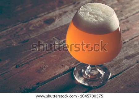 Glass of cold pale unfiltered beer on a rustic wooden pub table