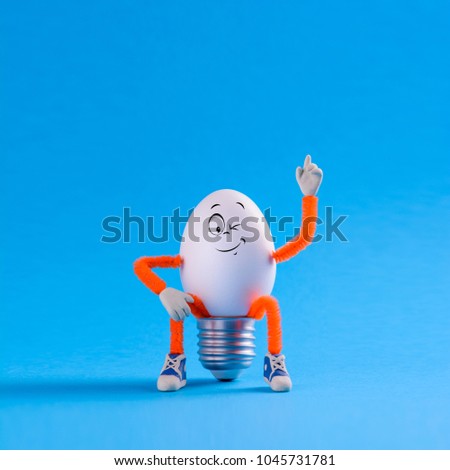 Winking Easter egg toy in the shape of a light bulb on a blue background. Innovation business concept idea.