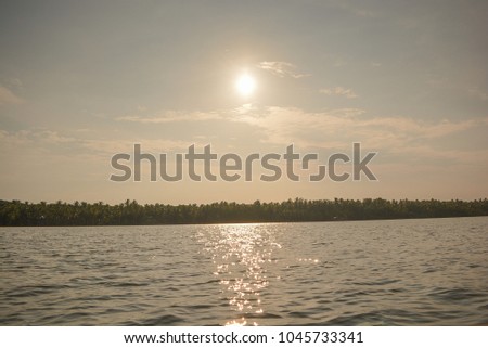 Beautiful sunset near beach, reflection of a sunset in water with coconut trees near kerala india