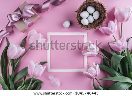 Easter eggs in nest and tulip flowers on spring background. Top view with copy space. Happy Easter card