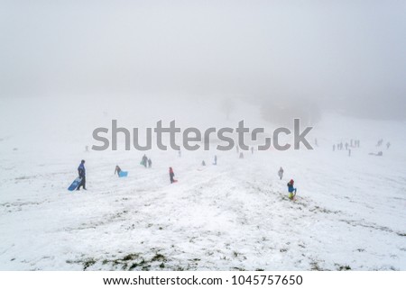 People enjoying snow skating on the slope on foggy morning after snow shower - winter scenery