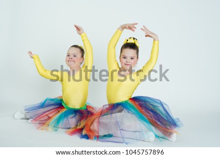 childhood in studio, girls dancing, wearing colorful skirts, doing exercise, Down syndrome, choreography on a white background, choreography in the soul Royalty-Free Stock Photo #1045757896
