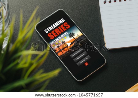 Tv series website app in a mobile phone screen, placed on a black desk.