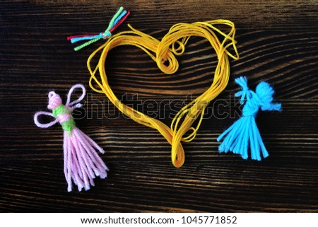 yellow and pink girl near yellow heart. Children's manual work. The figures woven from the colored thread.