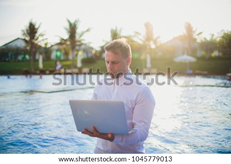 Young freelancer working on vacation next to the swimming pool