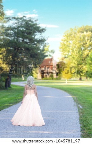 woman in evening tulle dress walking on road to estate home
