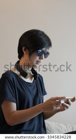 Asian woman hipster lifestyle using smartphone while using headphones and wearing eyeglasses