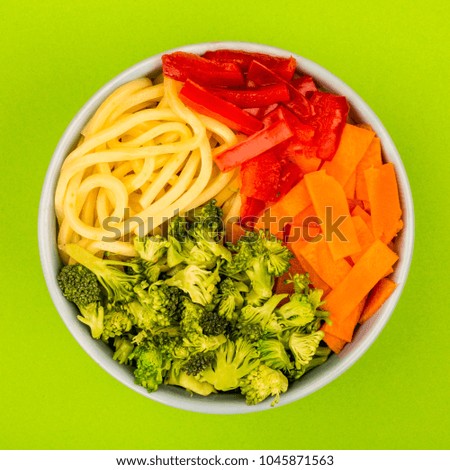 Healthy Vegetarian Hawaiian Style Poke Or Buddha Food Bowl, With Broccoli Carrots Red Peppers And Egg Noodles, Against A Green Background, Close Up With No People