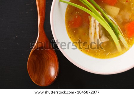 homemade chicken soup in white plate on black background