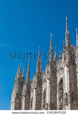 Some spiers surmounted by statues of the Milan Cathedral with a clear and blue sky